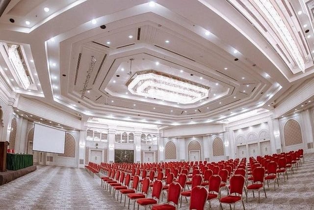 The Amir Temur conference hall at AZIMUT Grand Hotel Tashkent, with a stage, screen and rows of chairs